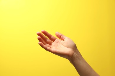 Woman holding something in hand on yellow background, closeup