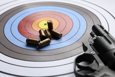 Photo of Handgun and bullets on shooting target, closeup
