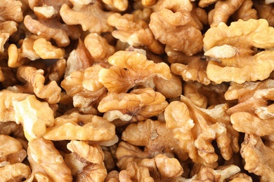 Photo of Many shelled walnuts as background, top view