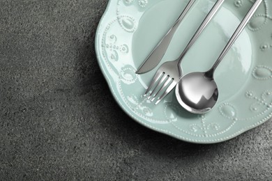 Photo of Stylish silver cutlery and plate on grey table, top view. Space for text