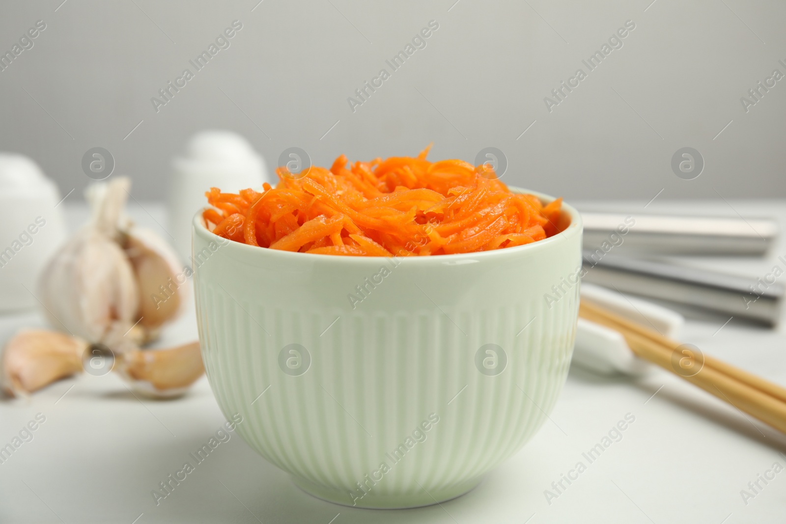 Photo of Delicious Korean carrot salad in bowl on white table