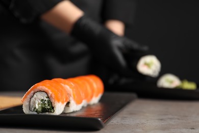 Tasty sushi rolls with salmon, cream cheese and cucumber on grey table, closeup