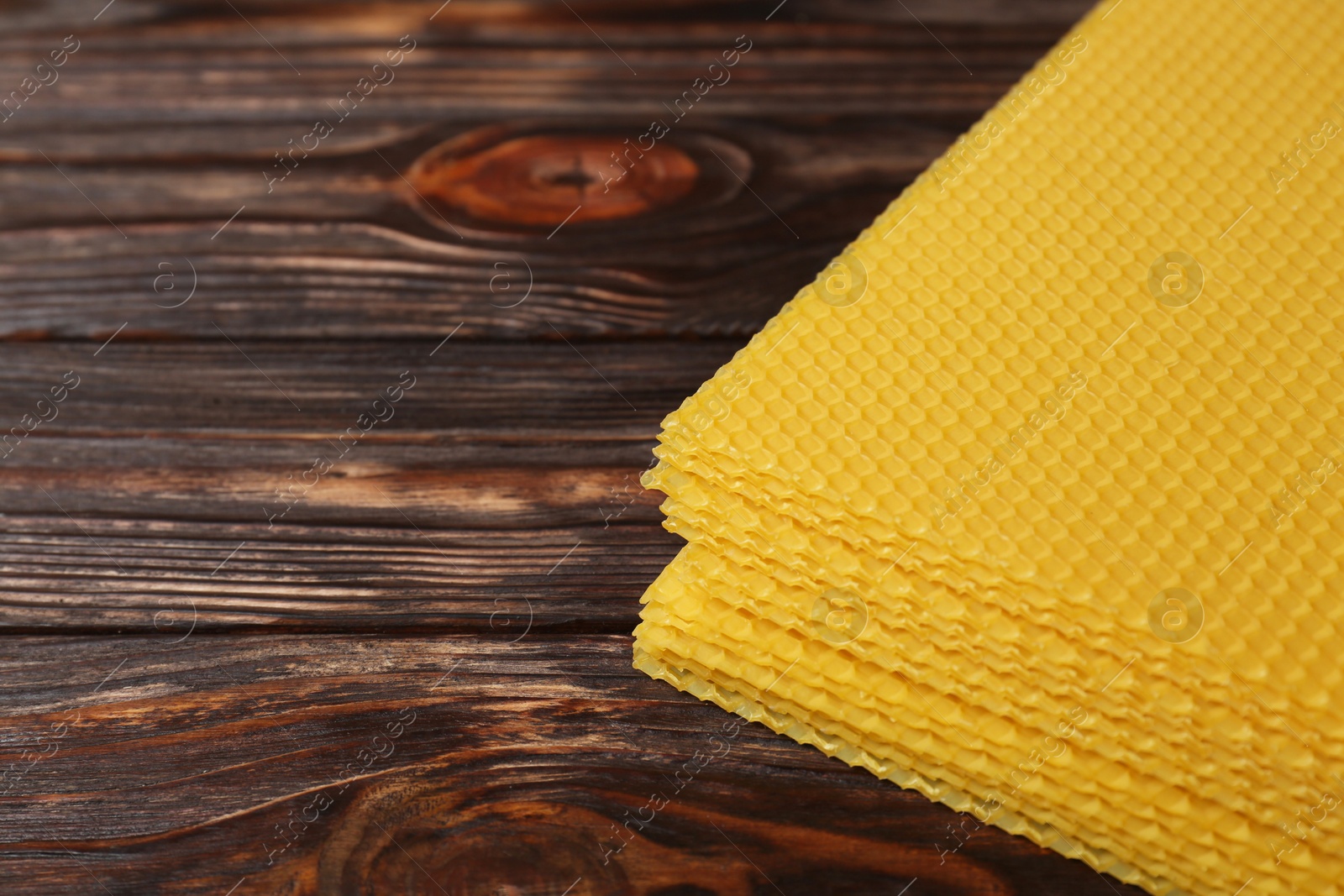 Photo of Natural beeswax sheets on wooden table, closeup. Space for text