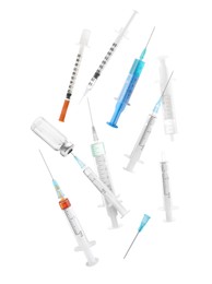 Different disposable syringes falling on white background. Medical equipment