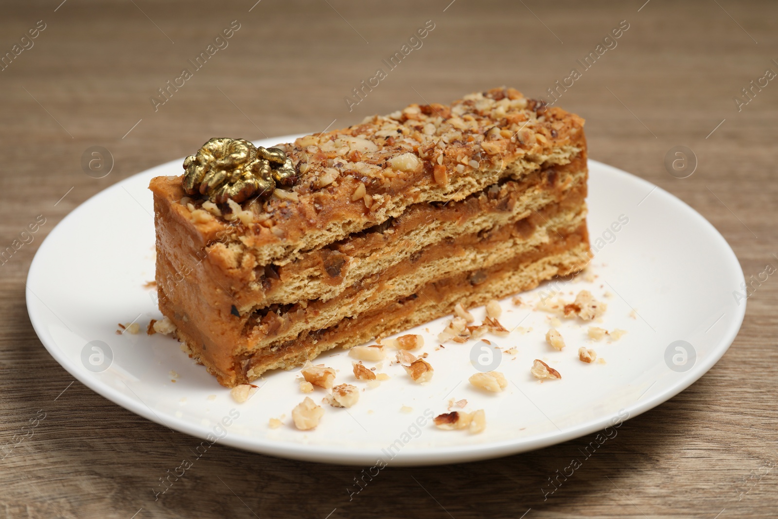 Photo of Plate with delicious layered honey cake on wooden table, closeup