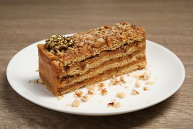 Plate with delicious layered honey cake on wooden table, closeup