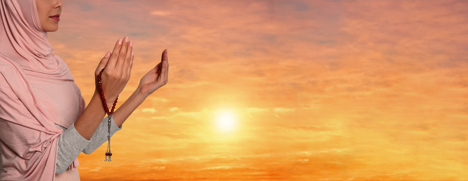 Image of Muslim woman praying outdoors at sunset, closeup. Banner design