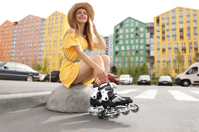 Photo of Beautiful young woman with roller skates outdoors, space for text