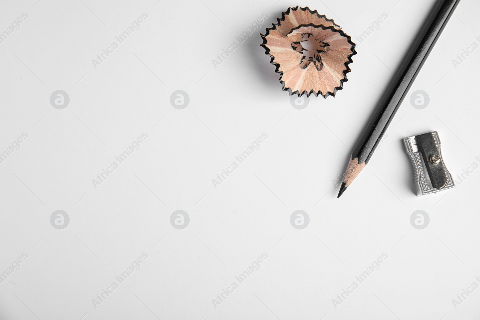 Photo of Pencil, sharpener and shaving on white background, top view