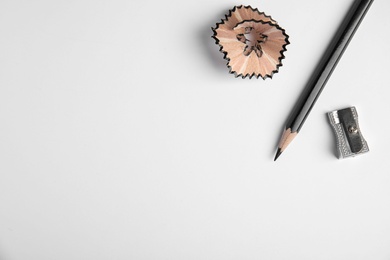 Pencil, sharpener and shaving on white background, top view