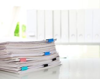 Stack of documents with paper clips on office desk. Space for text