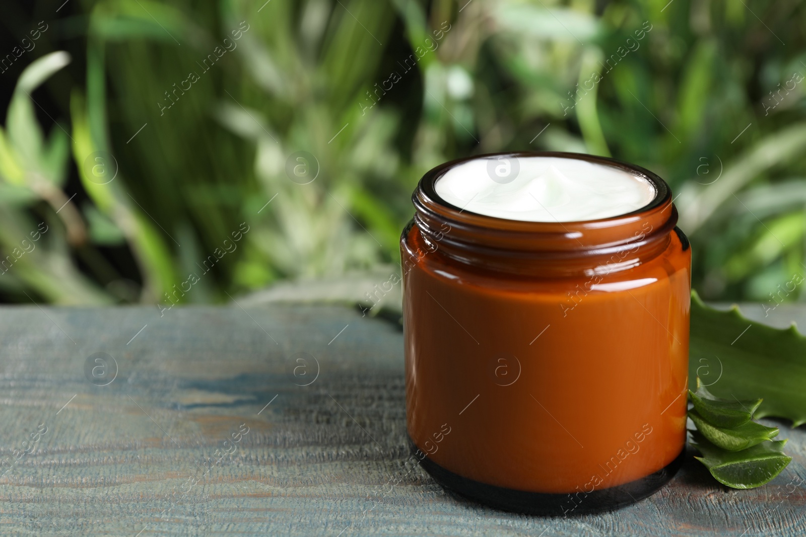 Photo of Jar of hand cream and aloe on light blue wooden table, space for text