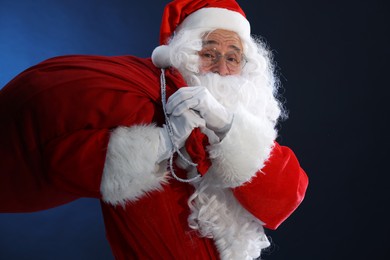 Photo of Merry Christmas. Santa Claus with bag on dark blue background