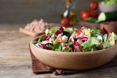 Photo of Bowl of delicious salad with canned tuna and vegetables on wooden table, space for text