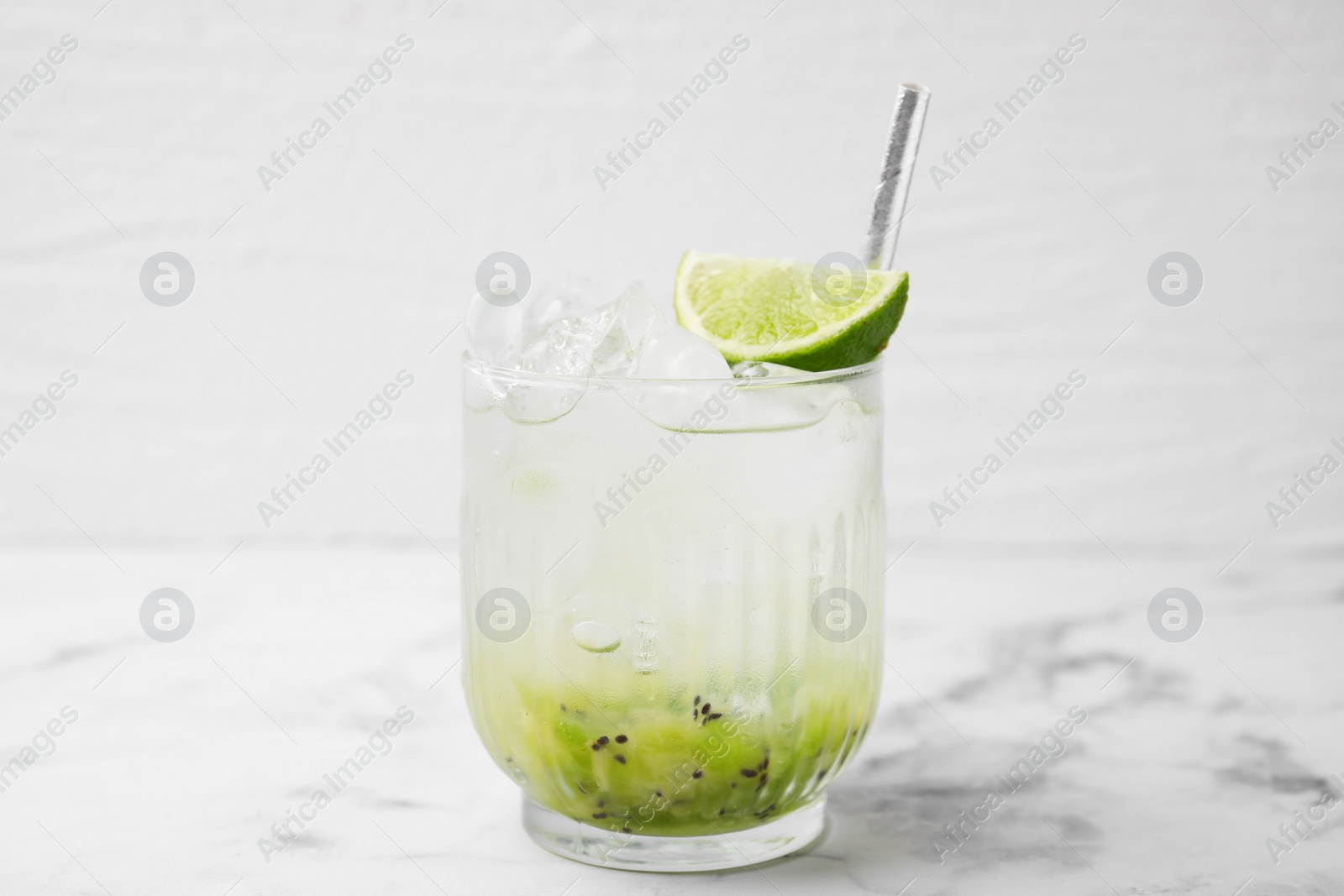 Photo of Glass of refreshing drink with kiwi and lime on white marble table