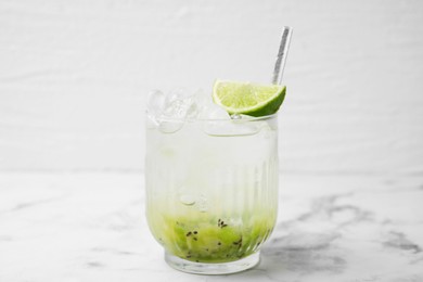 Photo of Glass of refreshing drink with kiwi and lime on white marble table