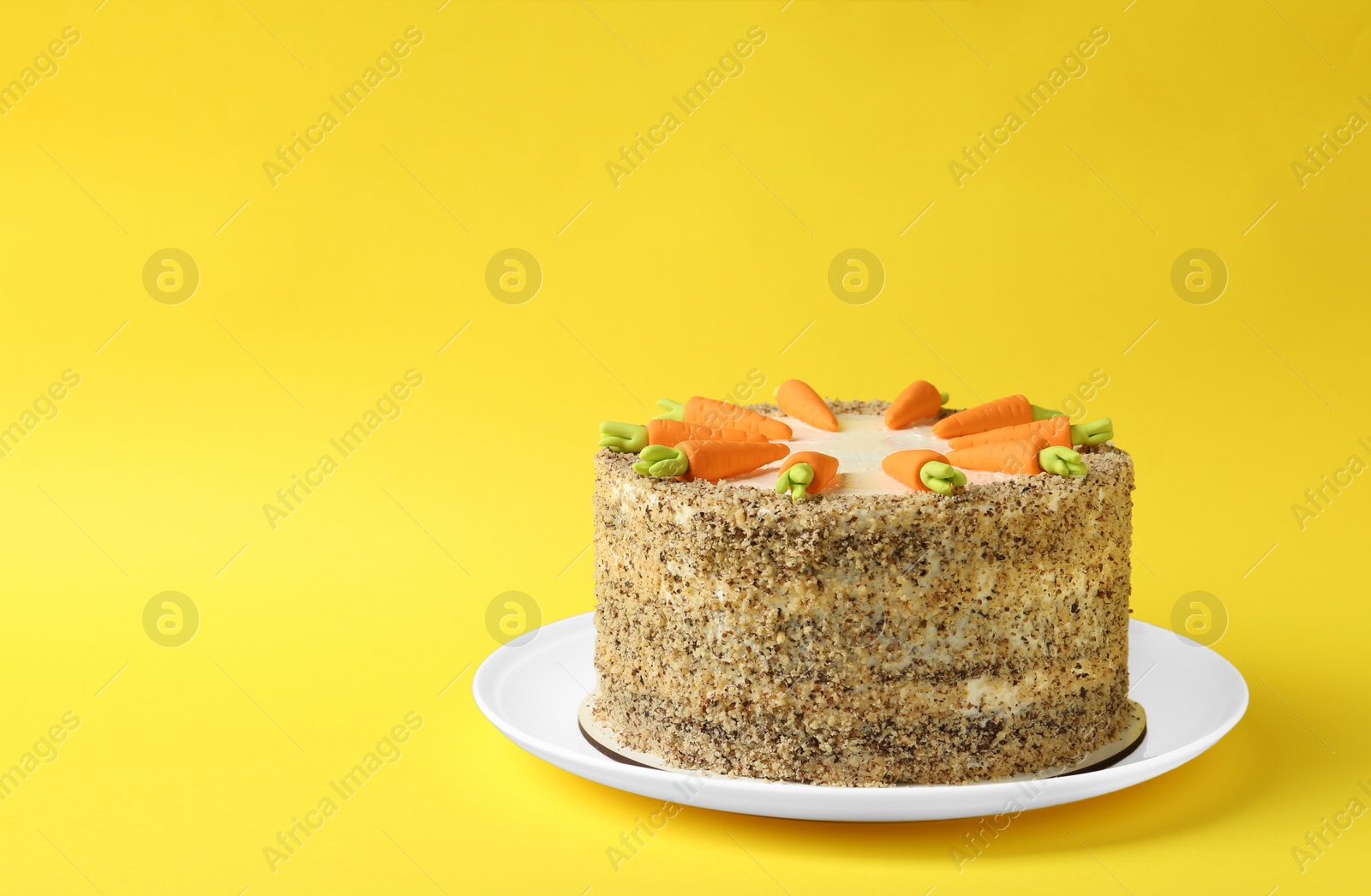 Photo of Dish with tasty carrot cake on yellow background, space for text