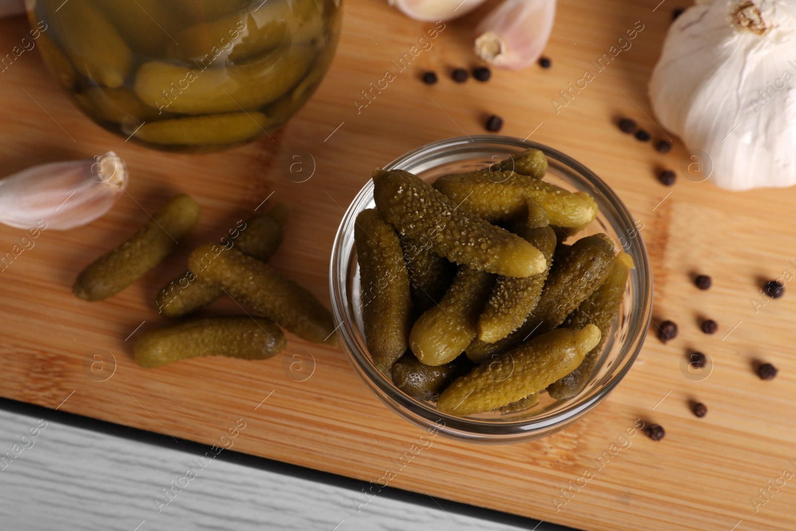 Photo of Tasty pickled cucumbers in glass bowl on wooden table, above view