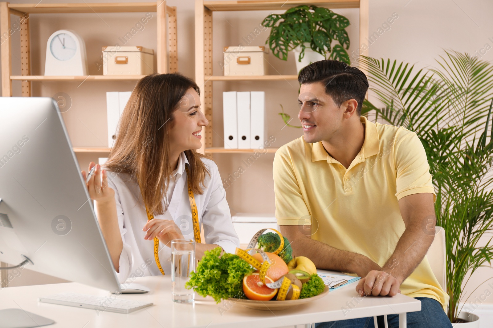 Photo of Young nutritionist consulting patient at table in clinic