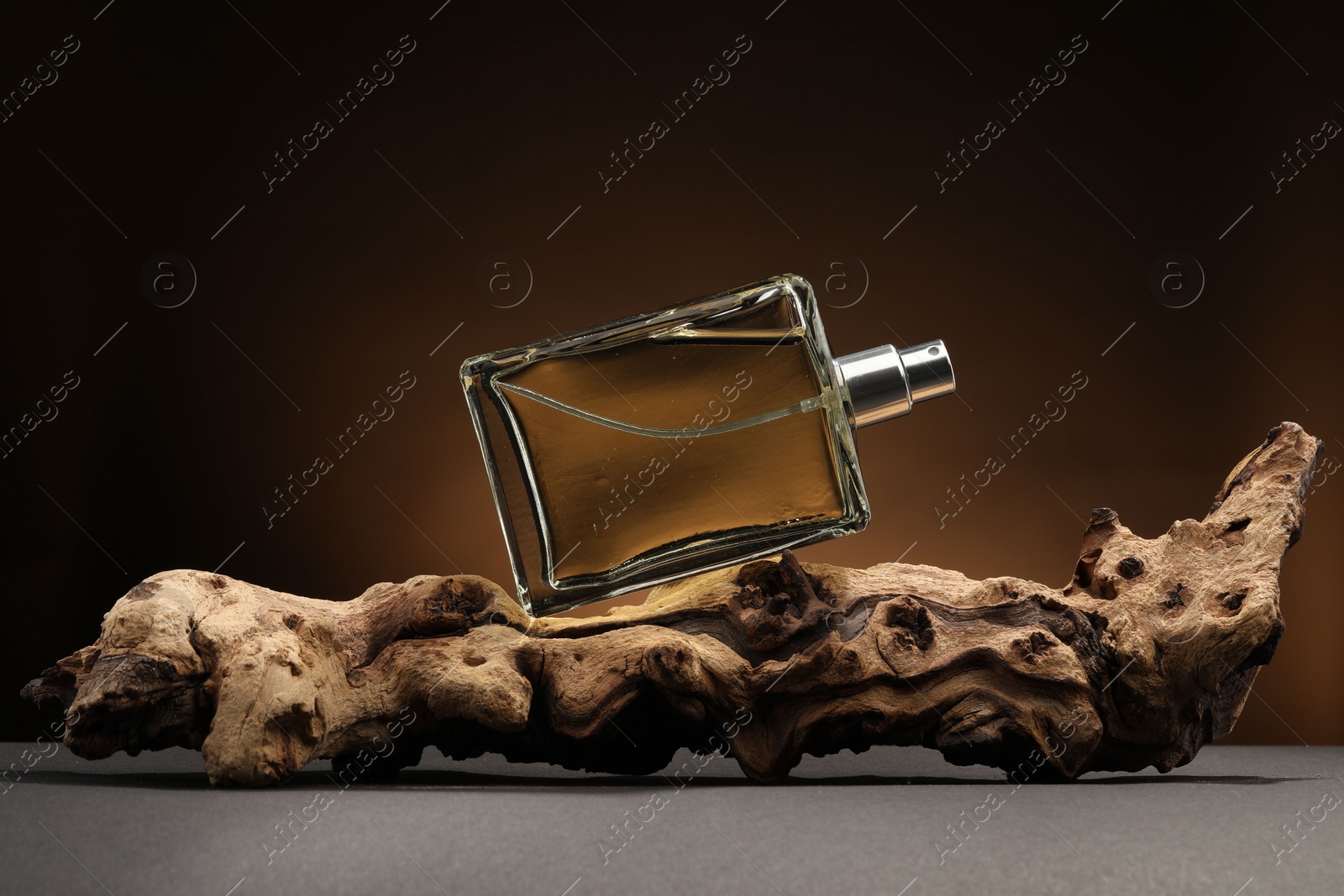 Photo of Luxury men`s perfume in bottle on grey table against dark background