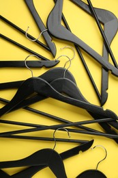 Photo of Black hangers on yellow background, flat lay