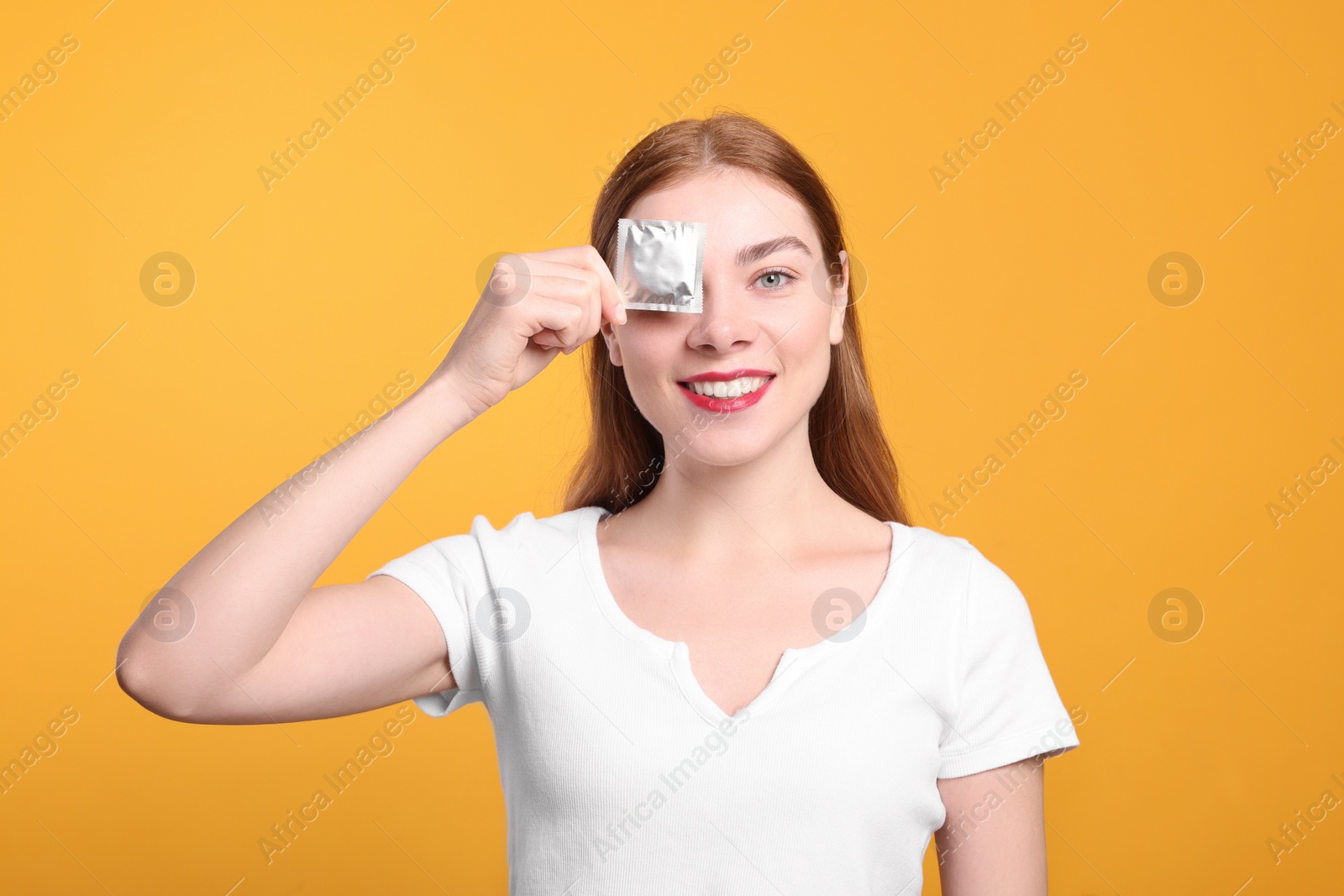 Photo of Woman holding condom on yellow background. Safe sex