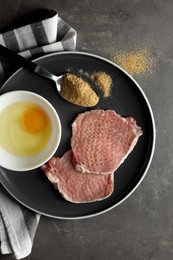 Plate with different ingredients for cooking schnitzel on grey textured table, top view