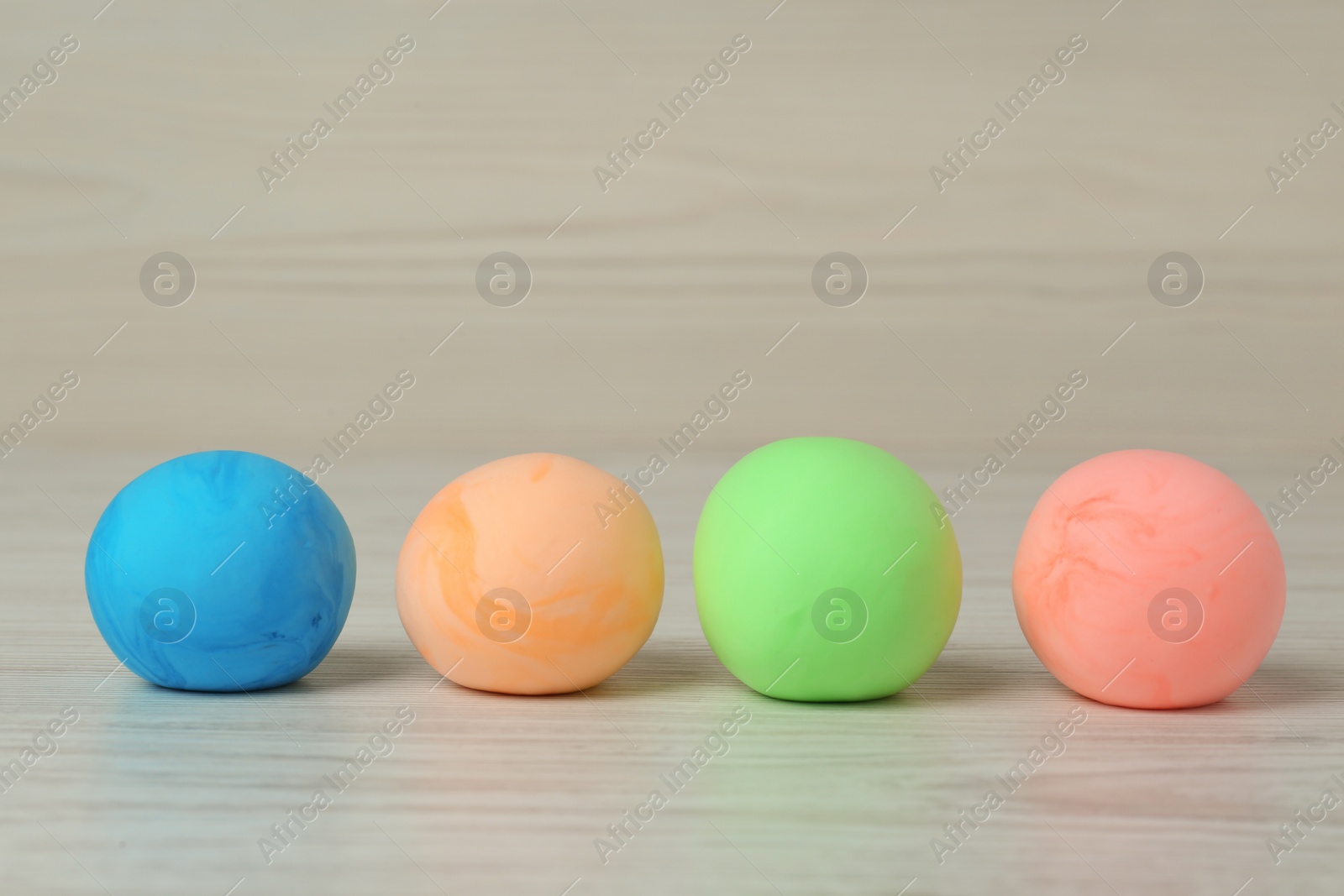 Photo of Different color play dough balls on white wooden table