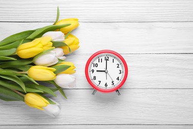 Photo of Red alarm clock and beautiful tulips on white wooden table, flat lay with space for text. Spring time