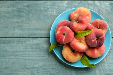 Fresh ripe donut peaches on light blue wooden table, top view. Space for text