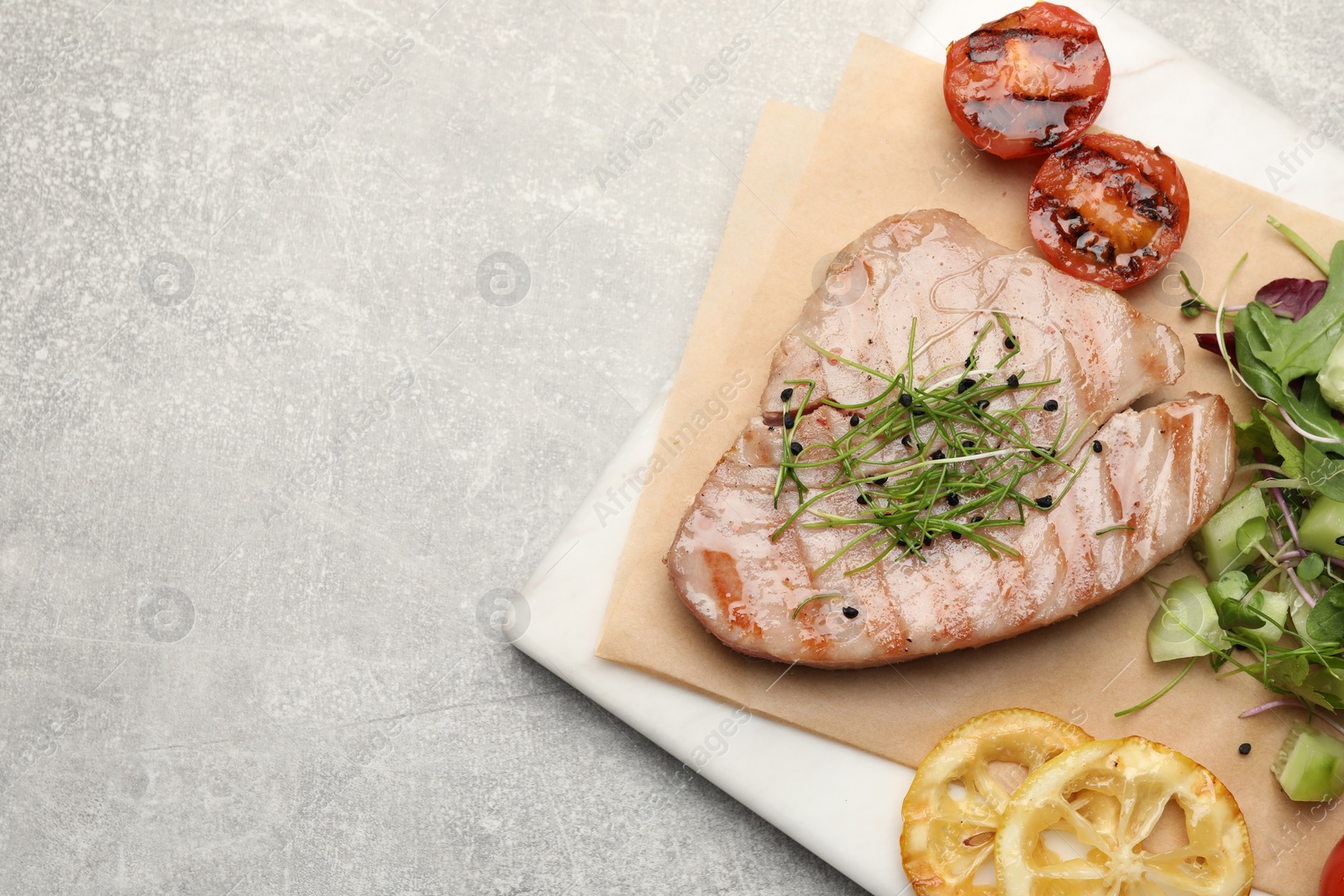 Photo of Delicious tuna steak served on light grey table, top view. Space for text