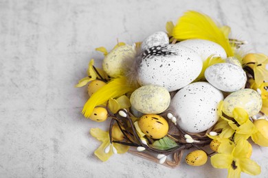 Photo of Decorative nest with many painted Easter eggs on light textured background