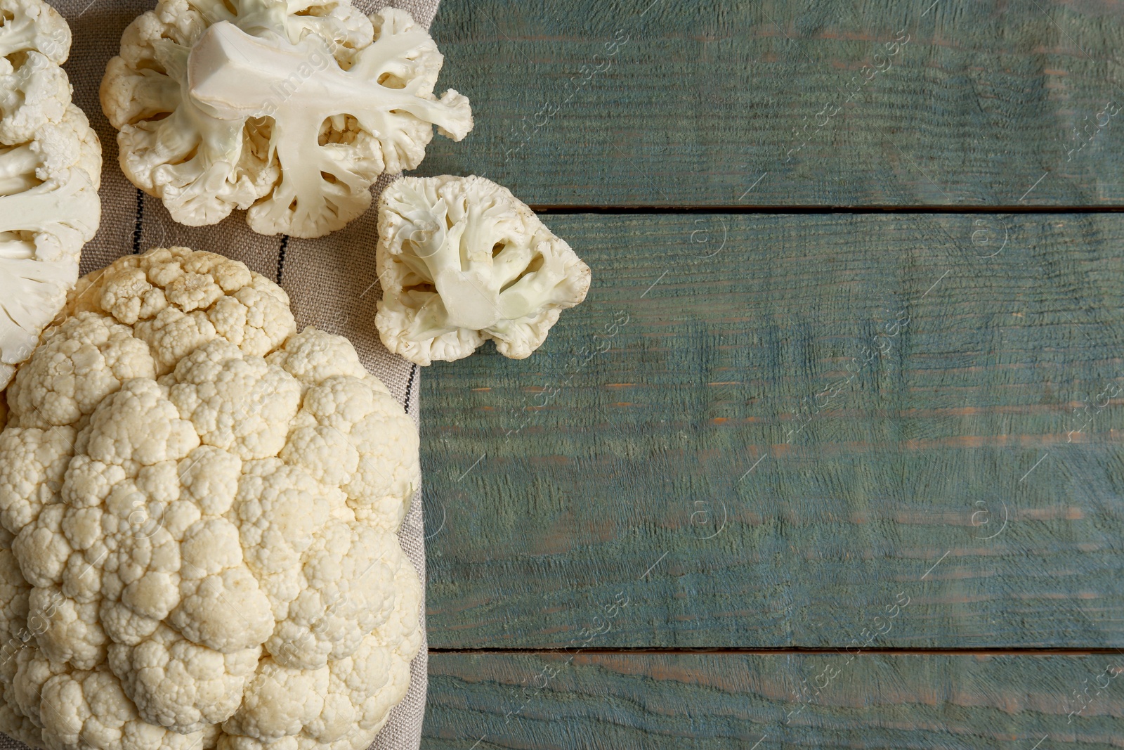 Photo of Fresh raw cauliflower on light blue wooden table, flat lay. Space for text