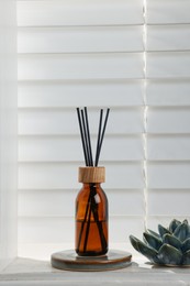 Air reed freshener and ceramic decor on white table near window