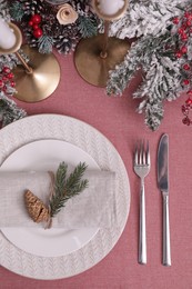 Photo of Festive place setting with beautiful dishware, cutlery and cone for Christmas dinner on pink tablecloth, flat lay