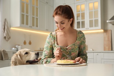 Cute dog begging for food while owner eating at table	