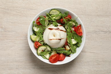 Photo of Delicious burrata salad on wooden table, top view