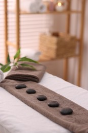 Towel with arranged spa stones on massage table in recreational center