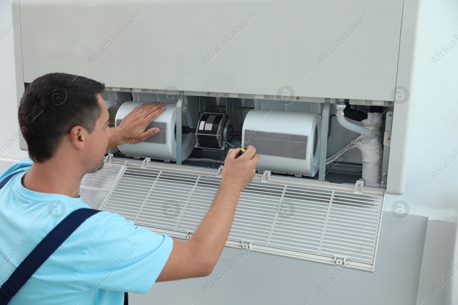 Photo of Technician repairing and checking air conditioner indoors