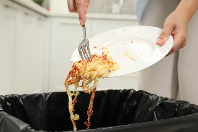 Photo of Woman throwing pasta into bin indoors, closeup