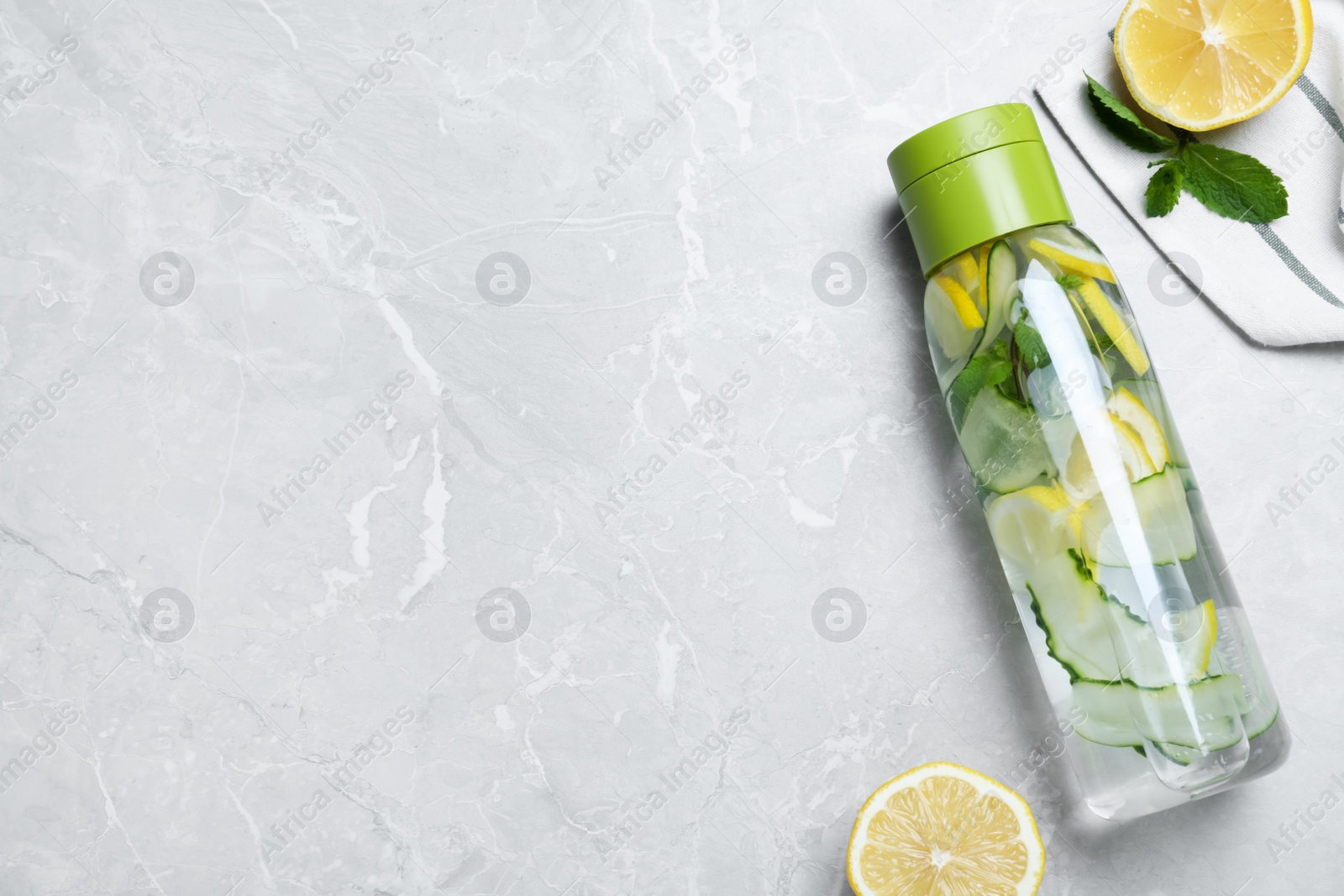 Photo of Bottle of refreshing water with cucumber, lemon and mint on light grey table, flat lay. Space for text