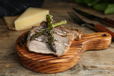 Photo of Tasty meat served with asparagus on wooden table