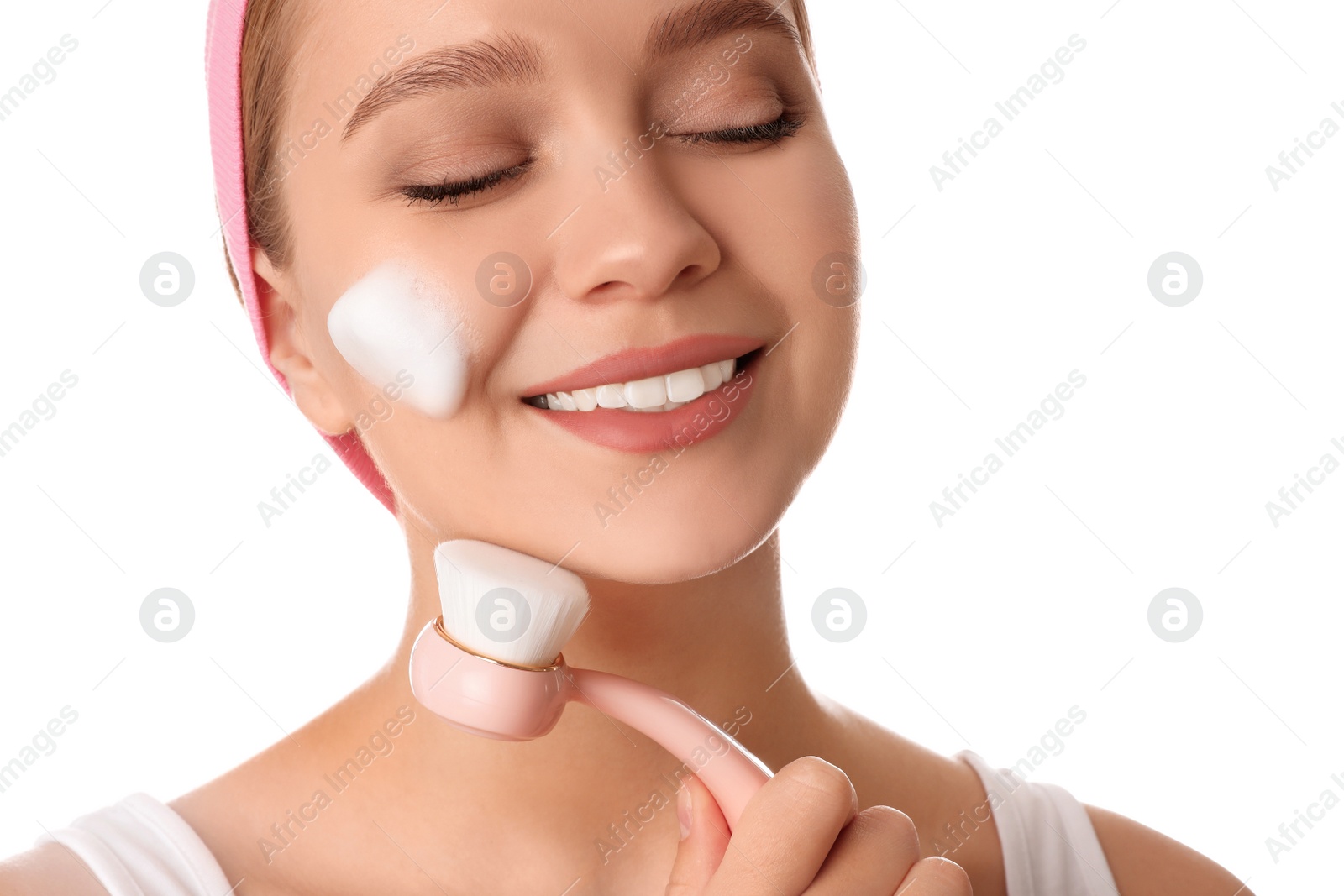 Photo of Young woman washing face with brush and cleansing foam on white background. Cosmetic products