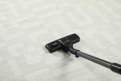 Photo of Removing dirt from white carpet with modern vacuum cleaner