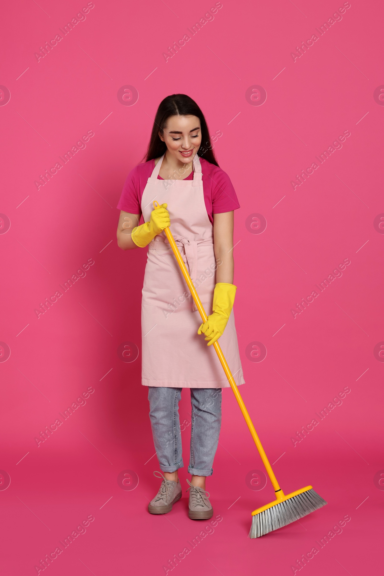 Photo of Beautiful young woman with broom on pink background