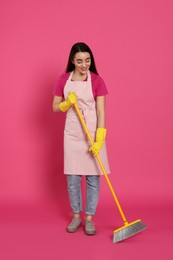 Beautiful young woman with broom on pink background