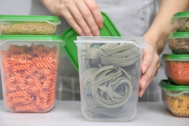 Photo of Woman with plastic containers filled of food products at light table indoors, selective focus