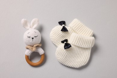 Baby accessories. Rattle and knitted booties on grey background, top view