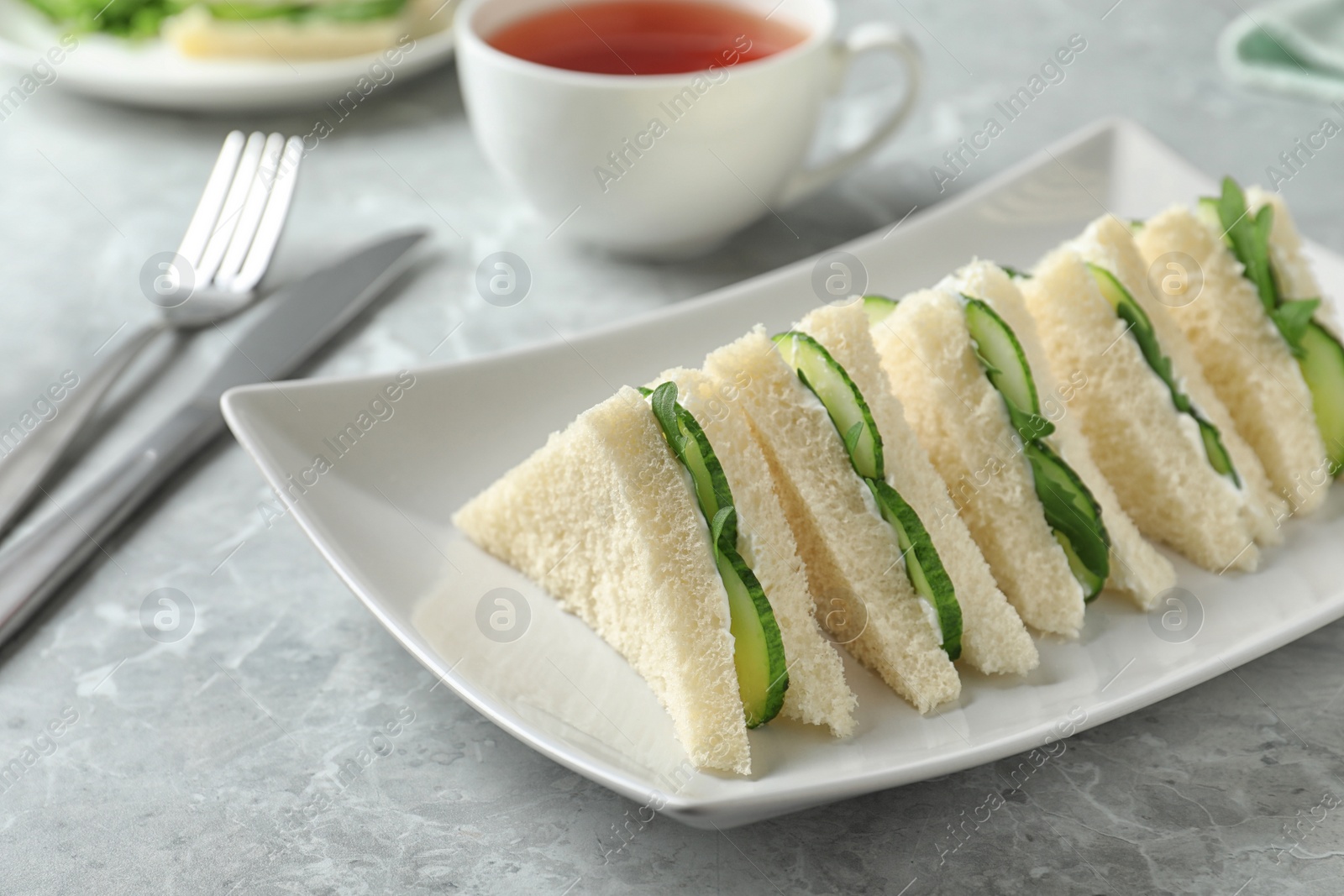 Photo of Plate with traditional English cucumber sandwiches on table