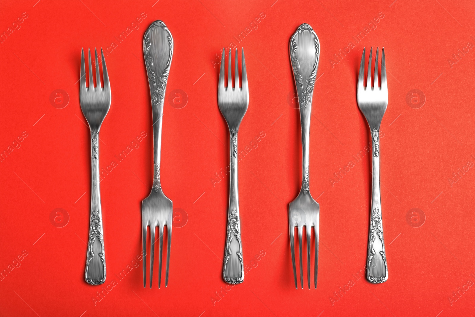 Photo of Vintage silver forks on red background, flat lay